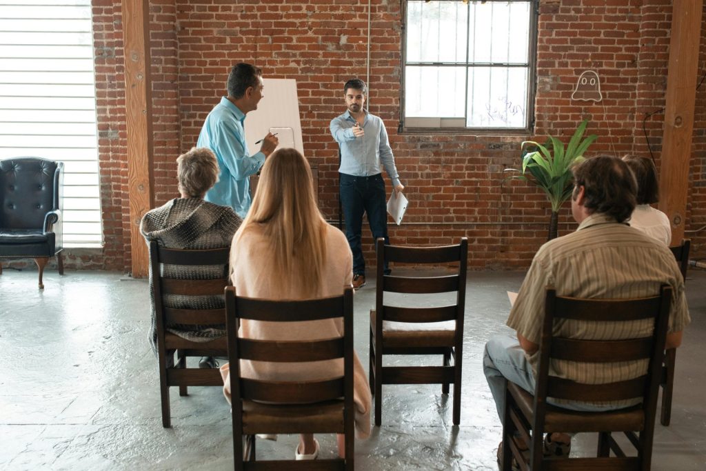 A group of adults attending an indoor workshop with a brick-wall backdrop.